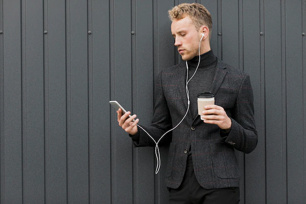 Person wearing headphones, listening to a podcast while holding a smartphone