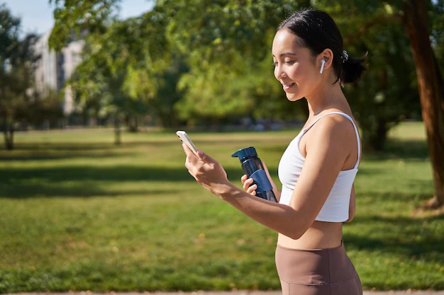 A woman using her smartphone while walking in a park