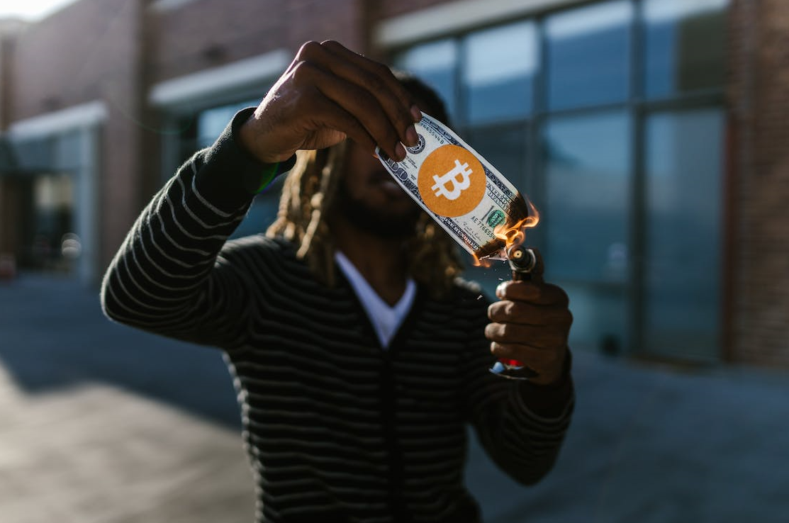 a man is holding a dollar with a Bitcoin image on it