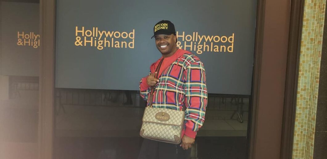 Rodney Bitcoin, stands on the background of the inscriptionHollywood&Highland